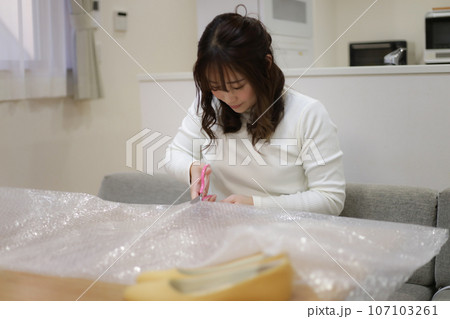 緩衝材を切る女性 107103261