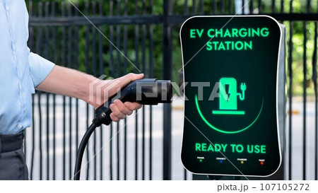 Businessman pull and hold EV charger plug form charging station. Peruse Businessman pull and hold EV charger plug form charging station. Peruse 107105272