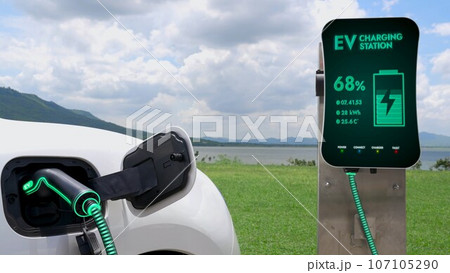Electric car plugged in with charging station with nature background. Peruse Electric car plugged in with charging station with nature background. Peruse 107105290