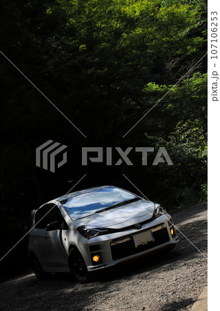 車と木漏れ日が差し込む田舎の風景 107106253