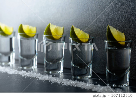 Tequila with lime and sea salt on a black table. 107112310
