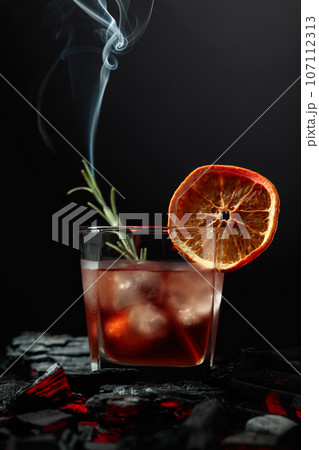 Whiskey with ice, orange slice, and burning rosemary. 107112313