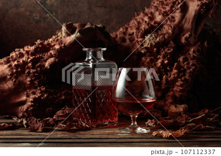 Decanter and glass of brandy on an old wooden table. 107112337