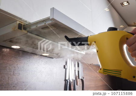 house cleaning. Girl brushes steam cleaners kitchen drawing with steam in green gloves. cleaning of a surface. house cleaning. Girl brushes steam cleaners kitchen drawing with steam in green gloves. cleaning of a surface. 107115886