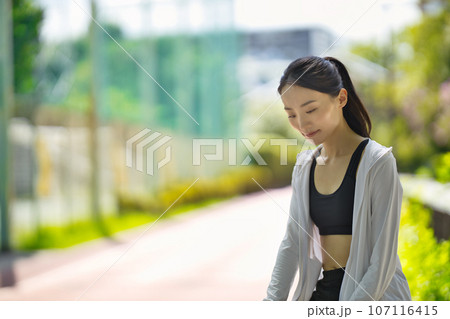 緑の中に佇むスポーツウェアの若い女性のポートレート 緑の中に佇むスポーツウェアの若い女性のポートレート 107116415