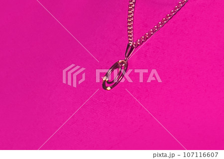 Gold pendant decoration chain close-up macro soft focus on pink background 107116607