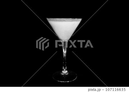 A martini glass with a white alcoholic beverage on an black background A martini glass with a white alcoholic beverage on an black background 107116635