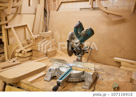 close up of a carpenter screwed a hinge on a wooden plank. 107116918