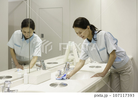 オフィスの洗面所で拭き掃除をするシニア女性清掃員 オフィスの洗面所で拭き掃除をするシニア女性清掃員 107117393