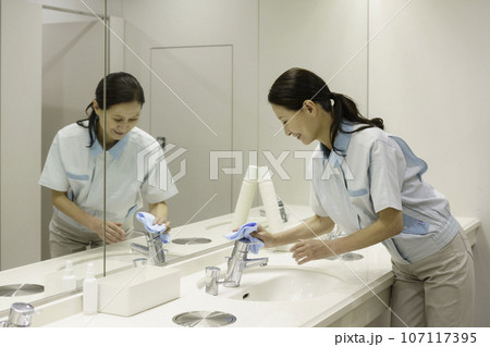 オフィスの洗面所で拭き掃除をするシニア女性清掃員 107117395