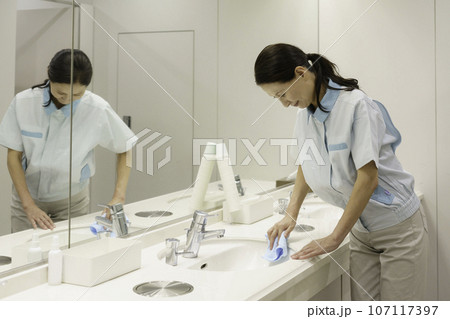 オフィスの洗面所で拭き掃除をするシニア女性清掃員 107117397