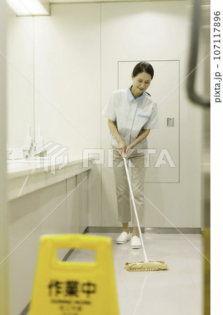 オフィスの洗面所の床にモップをかけるシニア女性清掃員 縦位置 オフィスの洗面所の床にモップをかけるシニア女性清掃員 縦位置 107117896