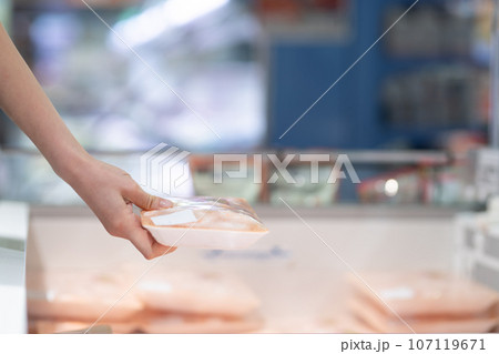 スーパーマーケットでパック入りの食材を手に取る女性の手 107119671
