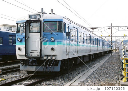 車両基地に停車する信州色の115系電車 107120396