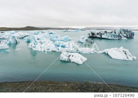 Luminous blue icebergs floating in  glacial lagoon with background of glacier mountain. 107120490