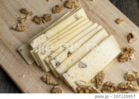 Sliced piece of milk cheese with walnuts Sliced piece of milk cheese with walnuts 107120957