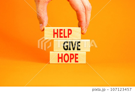 Help give hope symbol. Concept word Help give hope on beautiful wooden block. Businessman hand. Beautiful orange table orange background. Business motivational help give hope concept. Copy space. 107123457