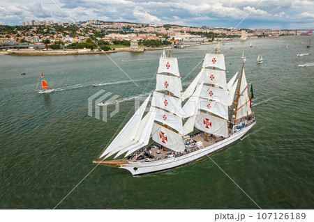 Aerial drone view of tall ships with sails sailing in Tagus river towards the Atlantic ocean in Lisbon, Portugal 107126189