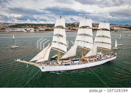 Aerial drone view of tall ships with sails sailing in Tagus river towards the Atlantic ocean in Lisbon, Portugal 107126194