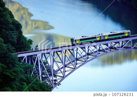 只見線　夏の第一只見川橋梁を渡る一番列車キハE120形(福島県三島町、8月中旬早朝) 107126231