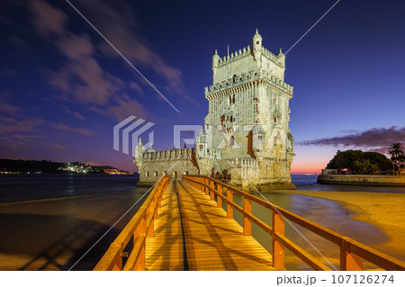 Belem Tower or Tower of St Vincent - famous tourist landmark of Lisboa and tourism attraction - on the bank of the Tagus River (Tejo) after sunset in dusk twilight with dramatic sky. Lisbon, Portugal 107126274