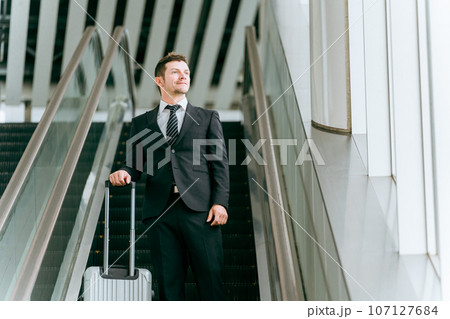 スーツケースを持って出張に行く欧米人ビジネスマン・海外出張・海外赴任・商社・貿易(エスカレーター) スーツケースを持って出張に行く欧米人ビジネスマン・海外出張・海外赴任・商社・貿易(エスカレーター) 107127684