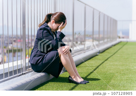 屋上で泣く・落ち込むビジネスウーマン（パワハラ・セクハラ・疲労・ストレス・困る・悩む・ハラスメント） 107128905