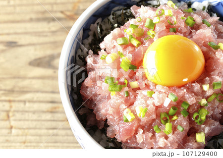小葱と卵黄が乗っているマグロのたたき丼を俯瞰で撮影 107129400