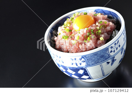 小葱と卵黄が乗っているマグロのたたき丼を黒背景で撮影 小葱と卵黄が乗っているマグロのたたき丼を黒背景で撮影 107129412