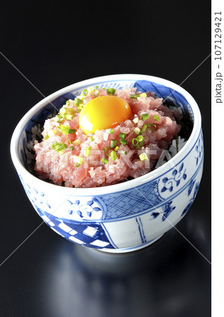 小葱と卵黄が乗っているマグロのたたき丼を黒背景で撮影 107129421