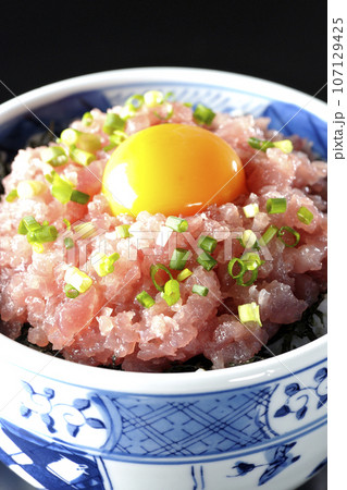 小葱と卵黄が乗っているマグロのたたき丼を黒背景で撮影 小葱と卵黄が乗っているマグロのたたき丼を黒背景で撮影 107129425