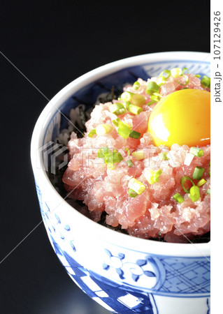 小葱と卵黄が乗っているマグロのたたき丼を黒背景で撮影 小葱と卵黄が乗っているマグロのたたき丼を黒背景で撮影 107129426