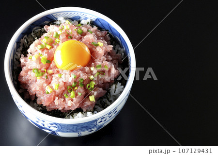 小葱と卵黄が乗っているマグロのたたき丼を黒背景で俯瞰撮影 107129431