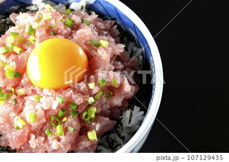 小葱と卵黄が乗っているマグロのたたき丼を黒背景で俯瞰撮影 107129435