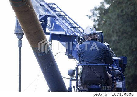 穴掘建柱車を操作して電柱の差し込みをする作業員男性 穴掘建柱車を操作して電柱の差し込みをする作業員男性 107130606