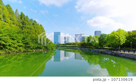 大阪城の堀水面を水鏡として映る木々とビル群 2023-08-21 大阪城の堀水面を水鏡として映る木々とビル群 2023-08-21 107130619