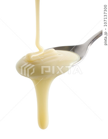 condensed milk pouring in spoon 107137300