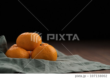 Organic tangerines on a linen napkin on a wood table Organic tangerines on a linen napkin on a wood table 107138002