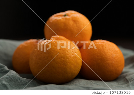 Organic tangerines on a linen napkin on a wood table 107138019