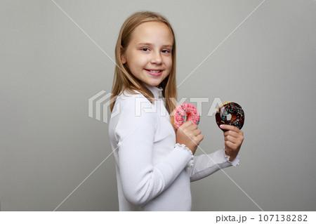 Kid and donut. Adorable happy child holding bright donut on white studio background Kid and donut. Adorable happy child holding bright donut on white studio background 107138282