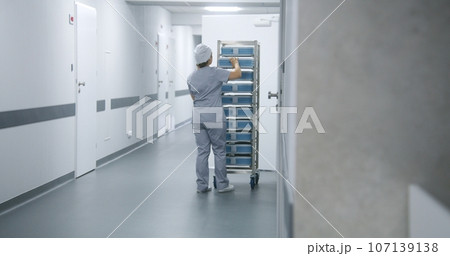 Nurse pushes mobile shelves with inventory through clinic corridor Nurse pushes mobile shelves with inventory through clinic corridor 107139138