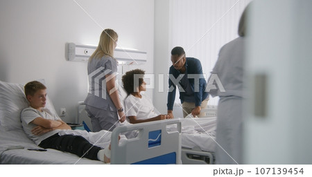 Mature physician bandages leg of young boy 107139454