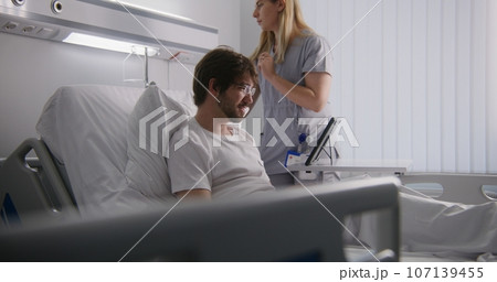 Man lies on bed in clinic and talks with partners 107139455