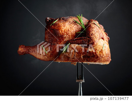 Smoked chicken on a fork sprinkled with rosemary. Smoked chicken on a fork sprinkled with rosemary. 107139477