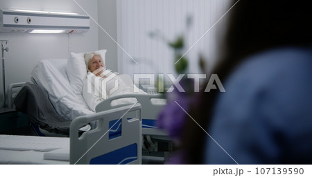 Family members come to elderly woman recovering after surgery 107139590