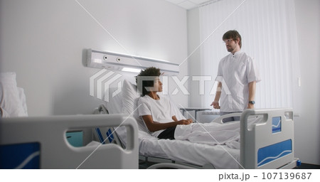Nurse bandages leg of young boy lying on bed Nurse bandages leg of young boy lying on bed 107139687
