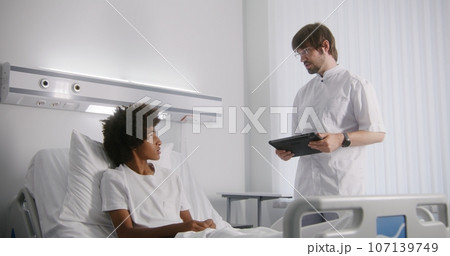 Nurse bandages leg of young boy lying on bed 107139749