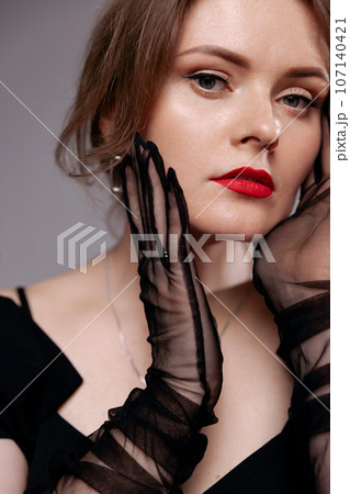 Red-lipped woman in black dress, looks at the camera. 107140421