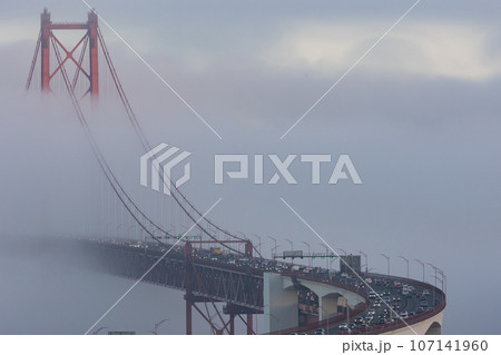 Cars driving across the bridge in the dense fog 107141960