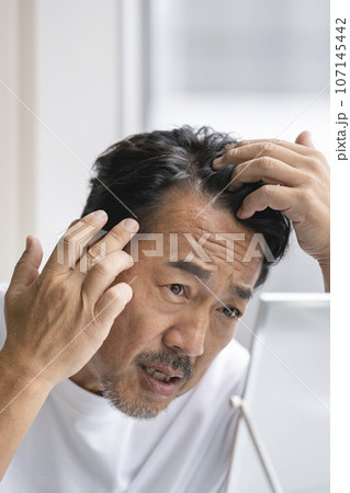 額の髪の生え際を気にする50代の男性 額の髪の生え際を気にする50代の男性 107145442